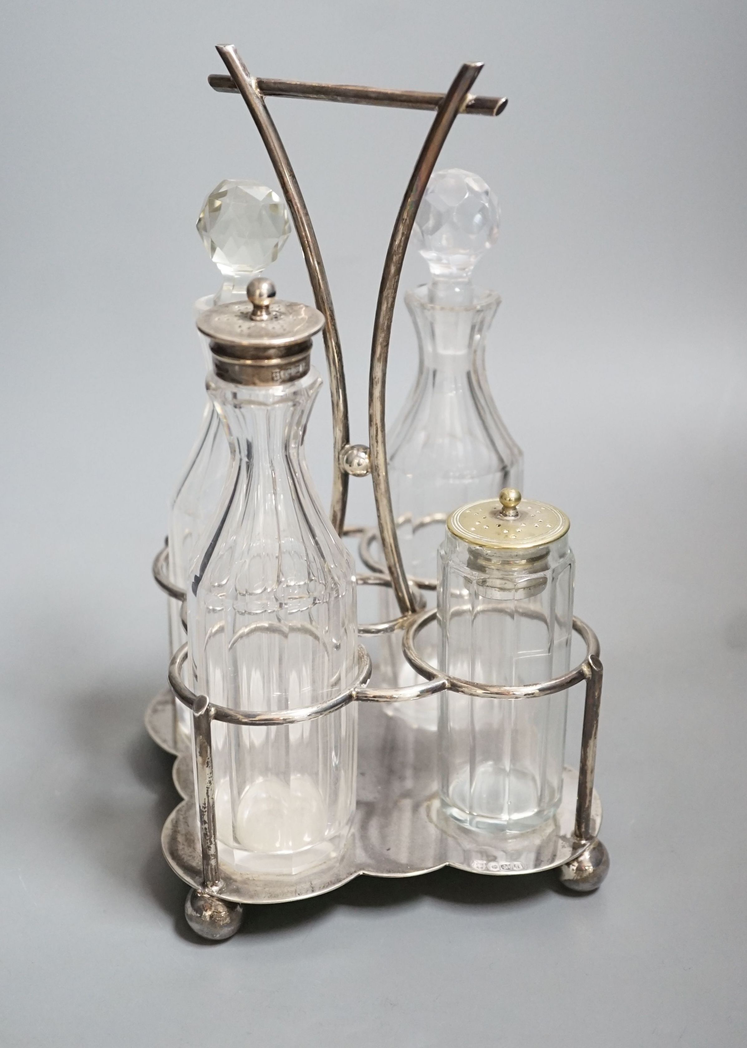 A George V silver four division cruet stand, Cooper Brothers & Sons, Sheffield, 1918, together with four glass cruets, one with silver mount and one associated, height 23.9cm, 13.50z.